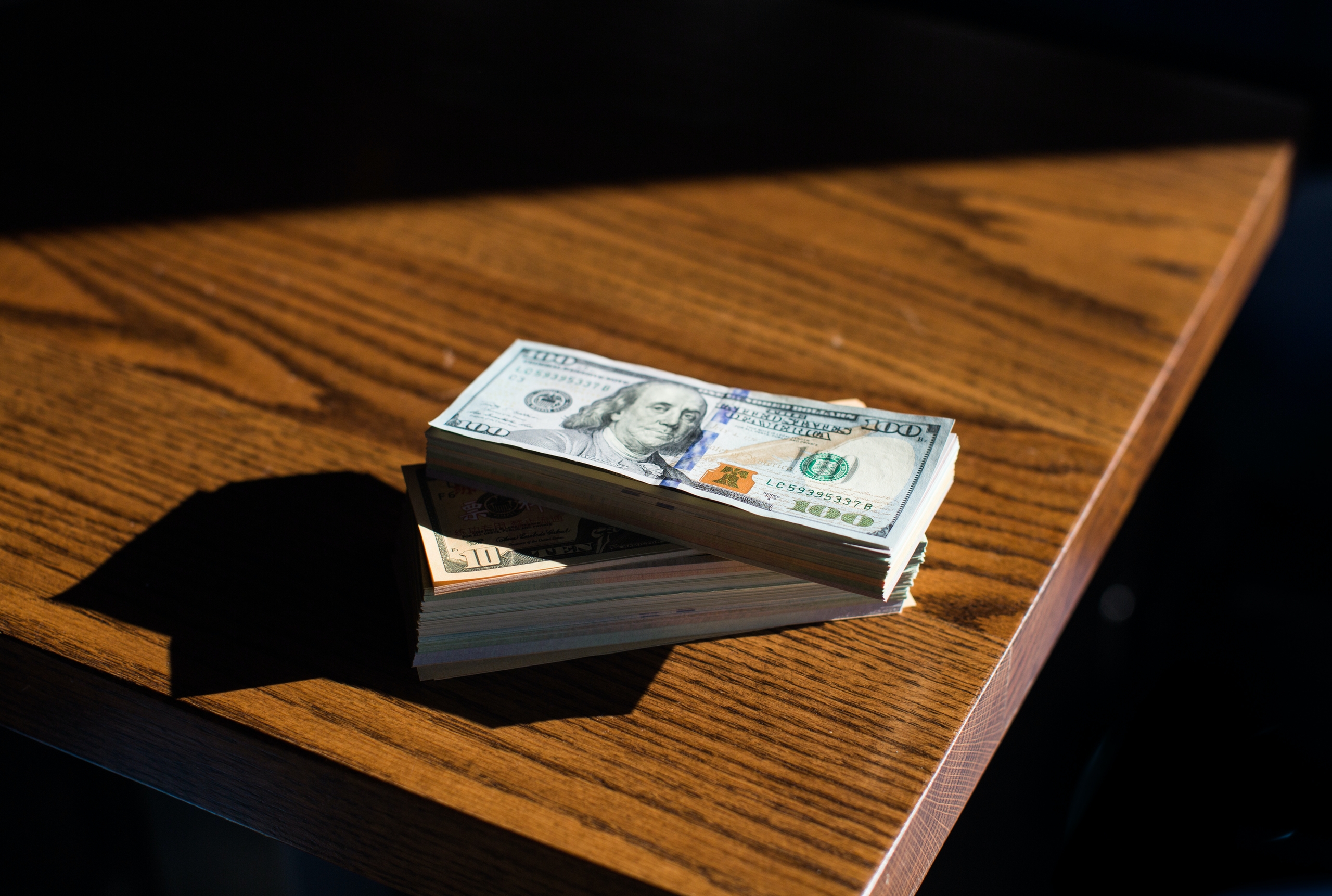 A stack of cash sits on a table as entrepreneurs decide how to set pricing.