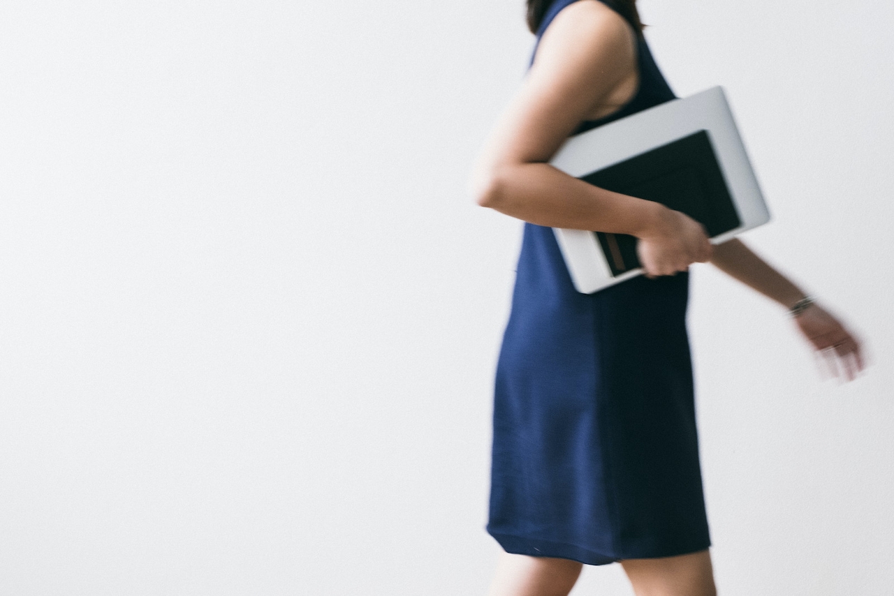 A woman in a blue dress walks towards a meeting about how to build an email list.