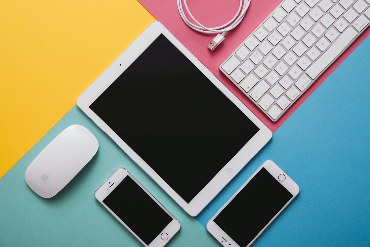 Two phones and a tablet are open for copywriting for a website on a multi-colored background.