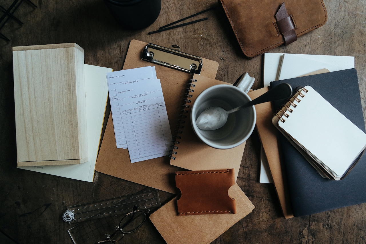 A flat lay for a blog post about "consistency is key" includes a clipboard, papers, and an empty coffee cup.