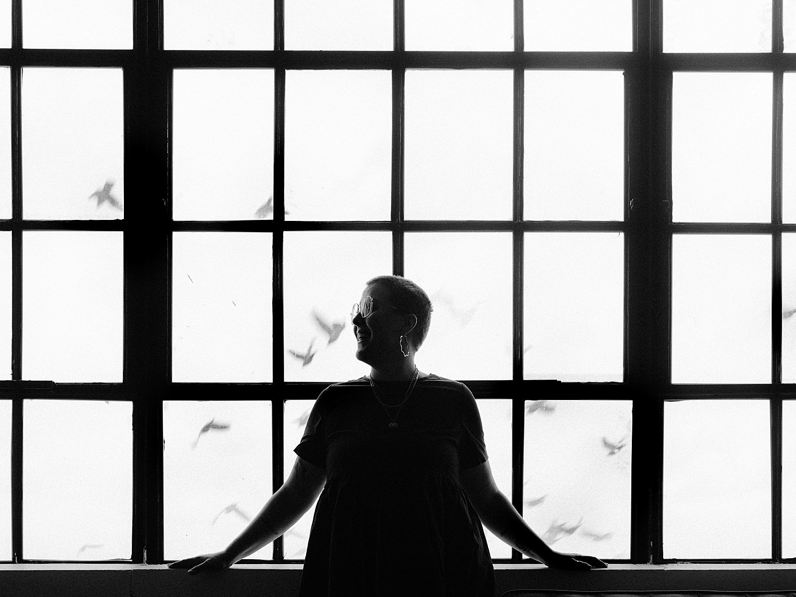 A copywriter stands in front of a tall window talking about sales copywriting.